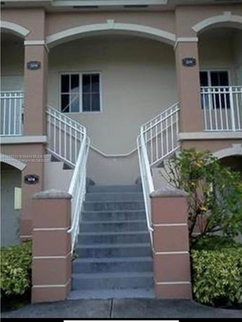 Front view of a two-story house with an arched entrance and staircase.