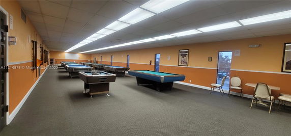 Recreational room with multiple pool tables and seating area.