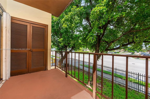 View from a building balcony with metal railing and trees in the background.