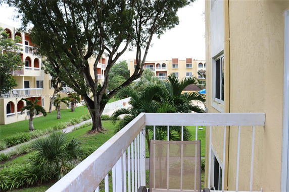 View from a building balcony overlooking an apartment complex and garden area.
