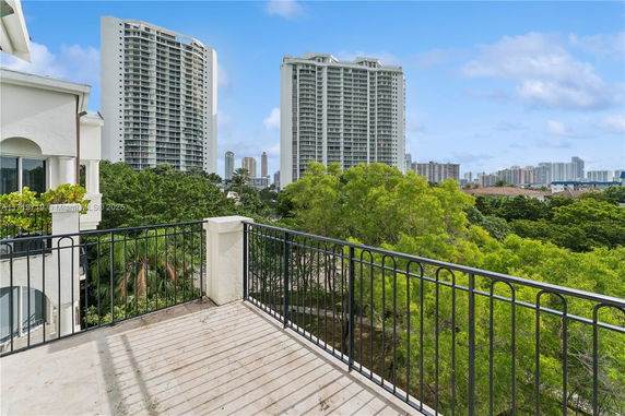 Panoramic view from a balcony showing high-rise buildings and greenery.