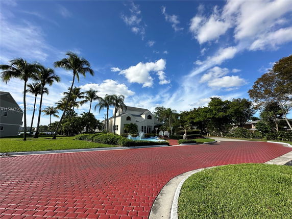 View of surrounding area with a two-story house and palm trees.