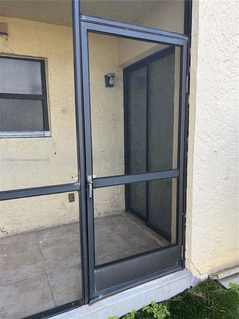 Screened outdoor porch area with glass door and textured wall.