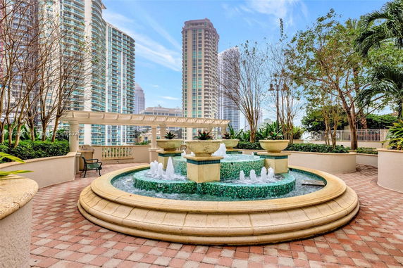 Fountain on a terrace with tall buildings in the background.