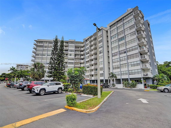 Front view of a multi-story residential building with balconies and parking area.