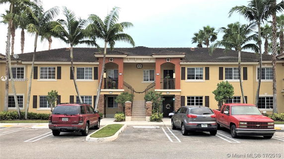 Front view of a two-story residential building with a parking area in front.