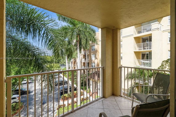 Balcony view with palm trees and neighboring buildings.