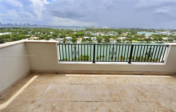 Balcony view overlooking water and distant city skyline.