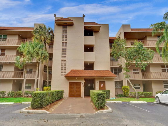 Front view of a multi-story apartment building with balconies and a central entrance.