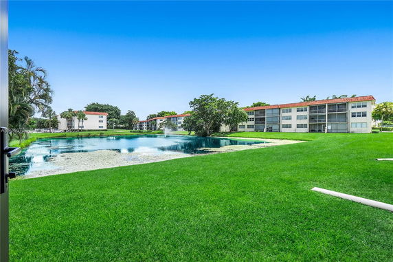View of several multi-story residential buildings with red roofs near a pond.