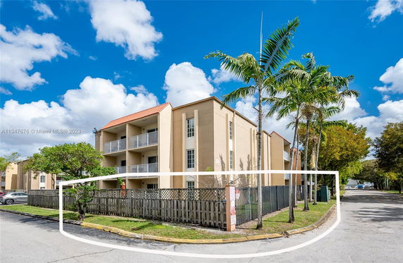 Front view of a multi-story residential building with balconies and a red-tiled roof.