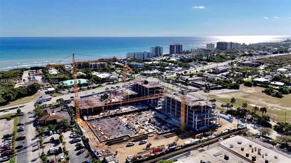 Aerial view of a construction site near the coastline with surrounding buildings and roads.