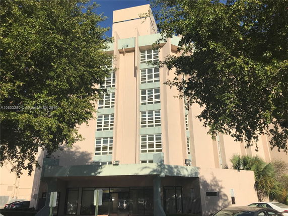 Front view of a multi-story building with large windows and a flat roof.