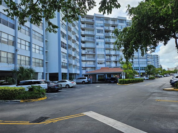 Front view of a multi-story residential building with parking area.