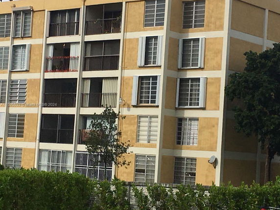 Front view of a multi-story apartment building with balconies and large windows.