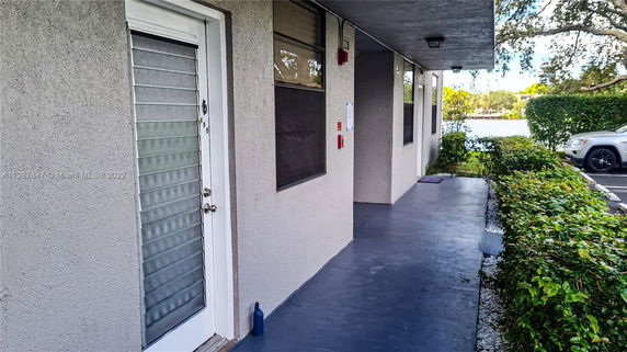 Front view of a building with a walkway and parked cars.
