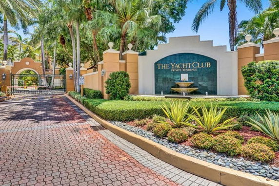 Entrance view of The Yacht Club private residence with decorative landscaping and signage.