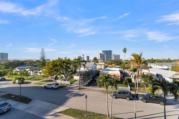 View of residential and commercial buildings along a street with parked cars.