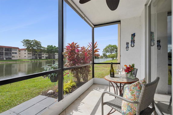 Screened patio area overlooking a pond and surrounding buildings.
