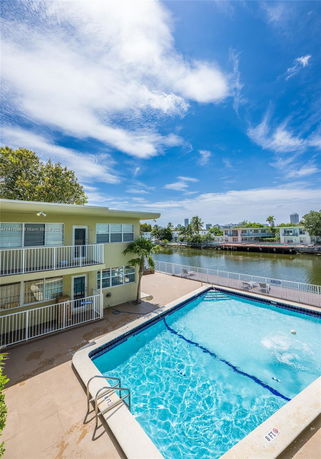 Swimming pool adjoining a building beside a waterway.