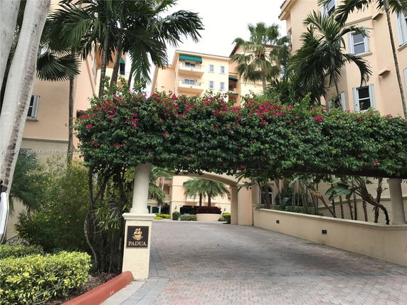 Front view of a multi-story building with balconies and decorative plants.