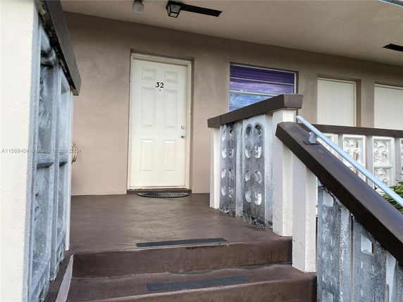 Front view of a building entrance with a door numbered 32 and a concrete stairway.