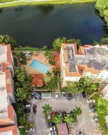 Aerial view of a residential area with buildings, a swimming pool, and a body of water.