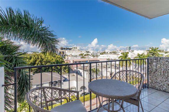 Balcony view overlooking cityscape with palm trees and buildings under a clear blue sky.