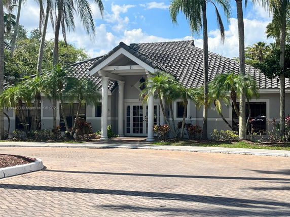 Front view of a single-story house with a tile roof and large pillars at the entrance.