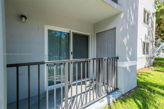 Exterior view showing a small balcony or patio area with railing and sliding glass doors on a building.