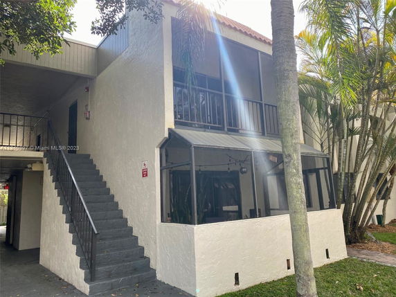 Front view of a two-story building with external stairs and a screened porch.