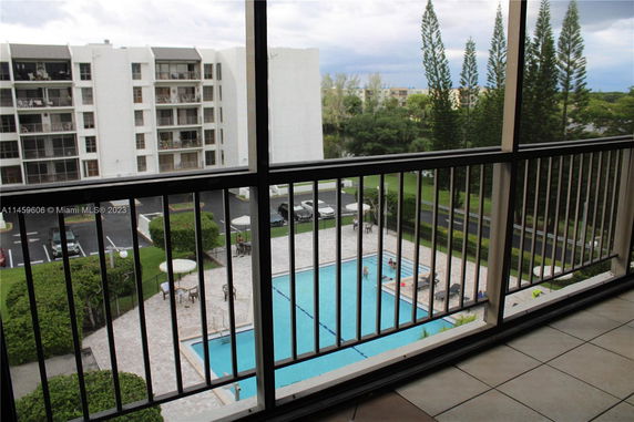 View from a balcony overlooking a swimming pool and apartment buildings.