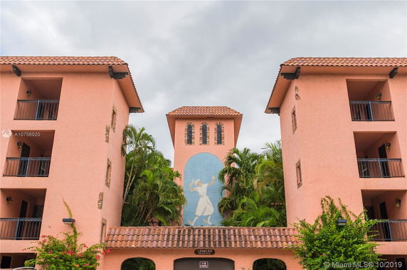 Front view of a multi-story building with a central mural and tile roofing.
