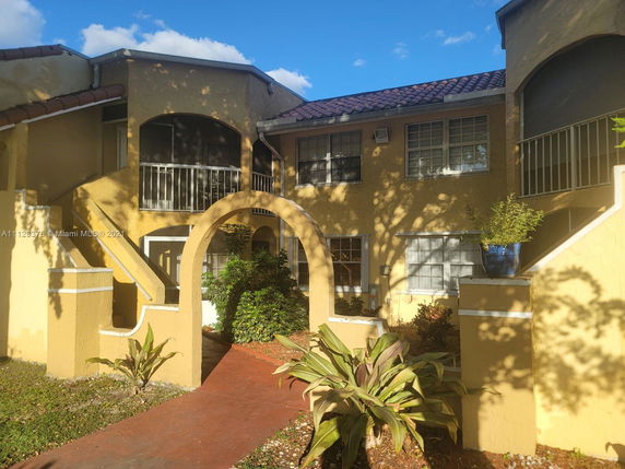 Front view of a multi-story apartment building with arches and staircases.