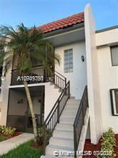 Front view of a two-story residential building with an external staircase and tiled roof.