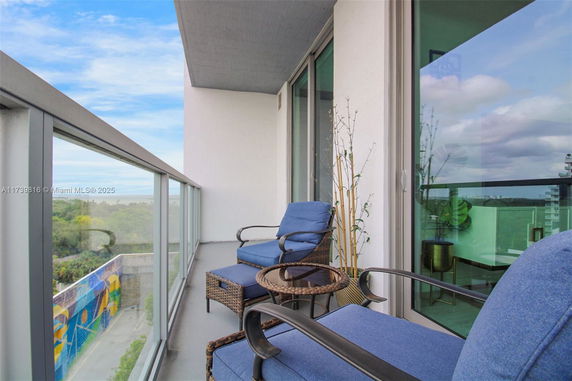 Outdoor balcony with chairs and a view of the surrounding landscape from a building.