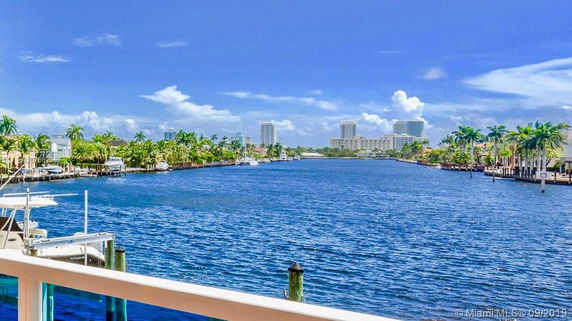 Panoramic view of a waterway with buildings and palm trees along the shore.