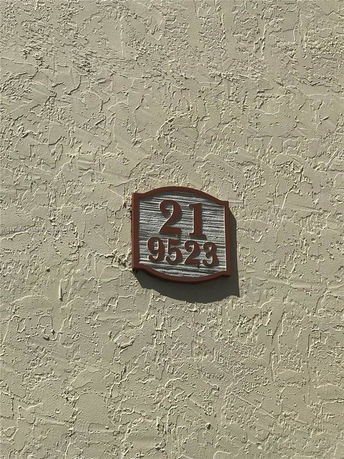 Textured exterior wall of a building with a number plaque.