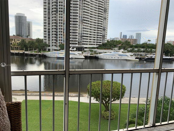 View from a building overlooking a waterway with yachts and surrounding high-rise buildings.