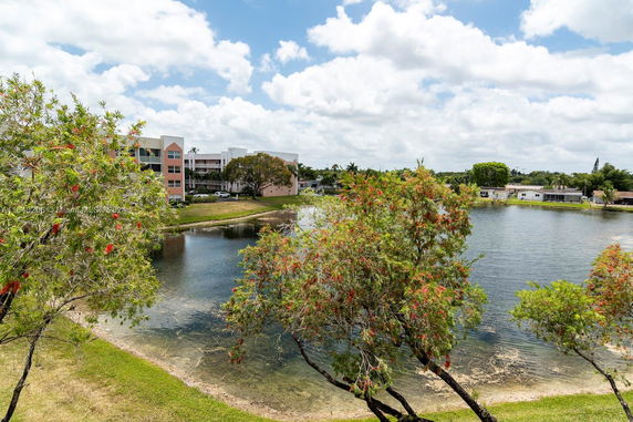 View of a lake with trees and residential buildings in the background.