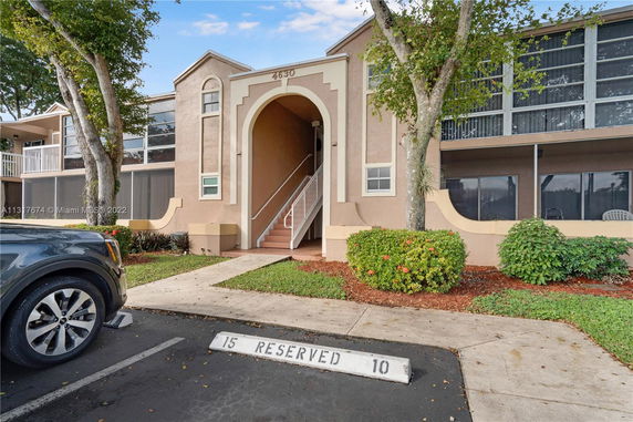Front view of a building with an archway entrance and screened balconies.