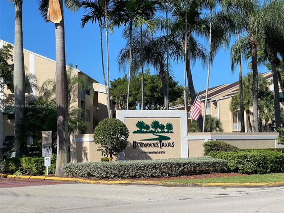 Entrance view of a condominium complex with surrounding palm trees.
