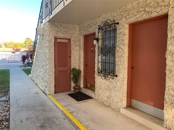 Front view of a building with textured stone exterior and metal window grille.