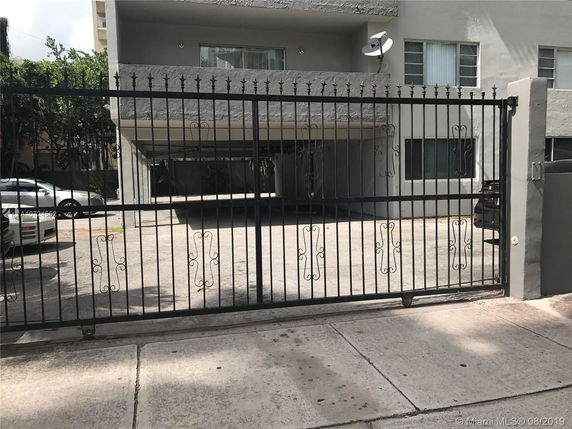 Front view of a multi-story building with a metal gate and a satellite dish.