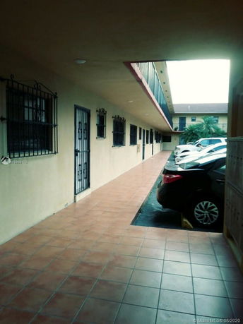 Outdoor parking area adjacent to a building with tiled walkway.