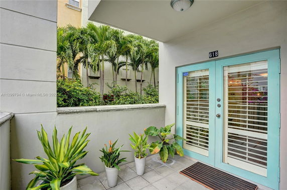 Entrance view of a building with turquoise-framed glass doors and potted plants.