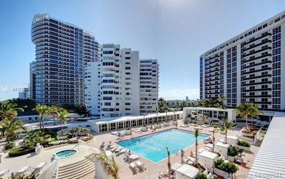 View of a residential complex with multiple high-rise buildings and a central swimming pool.