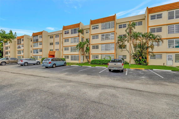 Front view of a multi-story apartment building with a parking area.