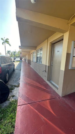 Front view of a building with a walkway and parked cars.