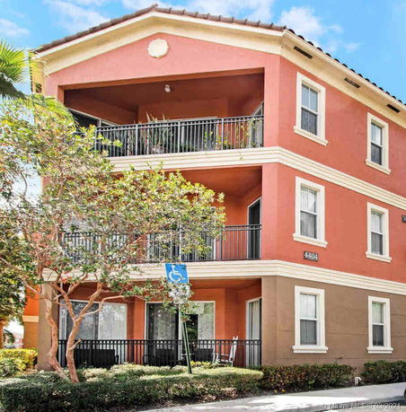 Front view of a three-story building with multiple balconies and a red color exterior.